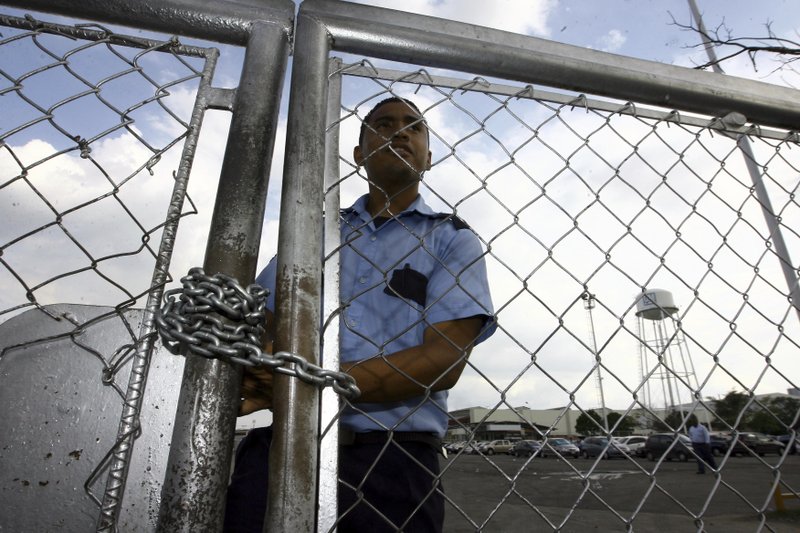 FILE - In this June 19, 2009 file photo, a security guard stands behind a fence at the General Motors assembly plant in Valencia, Venezuela. General Motors says it has halted operations in Venezuela after authorities seized a factory. The plant was confiscated on Wednesday, April 19, 2017, in what GM called an illegal judicial seizure of its assets. GM says its due process rights were violated and it will take legal steps to fight the seizure. (AP Photo/Juan Carlos Hernandez, File)
