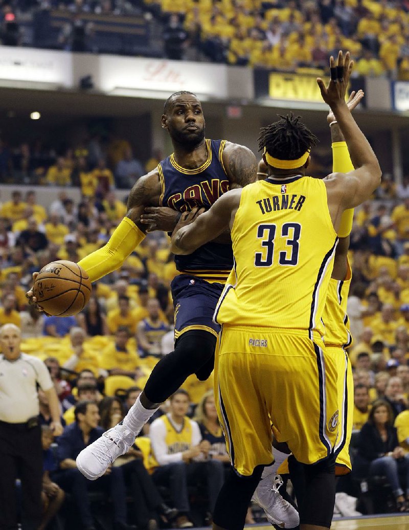 Cleveland forward LeBron James (left) wraps a pass around Indiana defender Myles Turner in the first half of Thursday night’s NBA Eastern Conference playoff game. James scored 28 of his 41 points in the second half to rally the Cavaliers back from a 25-point, halftime defi cit to beat the Pacers 119-114.