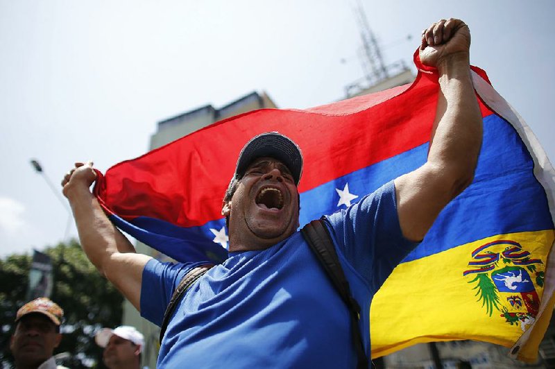 A demonstrator in Caracas joins another day of protests Thursday against Venezuelan President Nicolas Maduro, whose government seized a General Motors plant Wednesday.