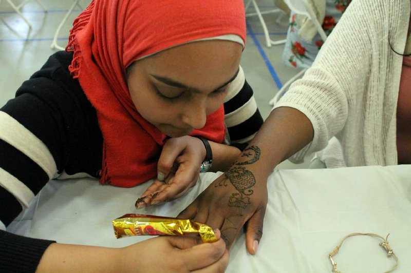 Mariam Khan (left) applies henna to the hand of Janecia Collins at the Little Rock International Food Festival on April 15. Khan has been working with henna, the temporary body dye prepared from the plant of the same name, for about 10 years. 