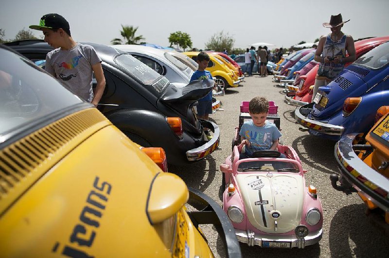 A child sits in a toy Volkswagen Beetle during a gathering Friday of devotees of the vehicle in Yakum, Israel. In the United States, Volkswagen is trying to put the scandal over emissions cheating behind it.