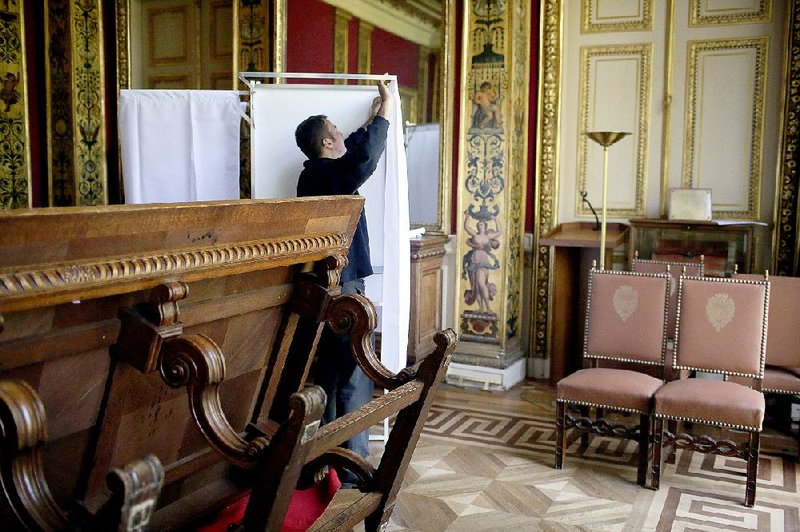 A worker prepares a polling booth in Paris ahead of the fi rst round of presidential voting in France that takes place Sunday.
