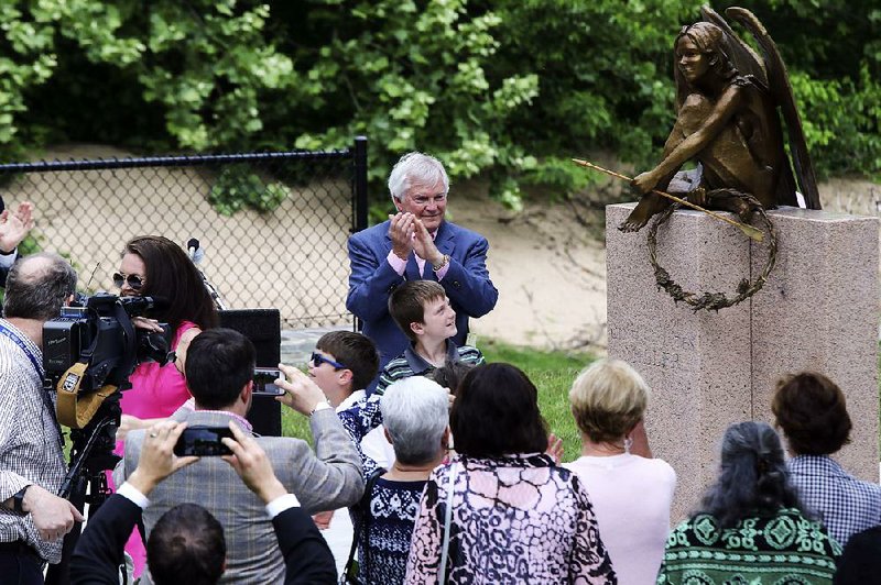 Pat Miller (center), husband of Cindy Coates Miller, applauds the unveiling and dedication of the Cindy Coates Miller Bridge and an accompanying angel sculpture Friday at the Clinton Presidential Park in Little Rock. 