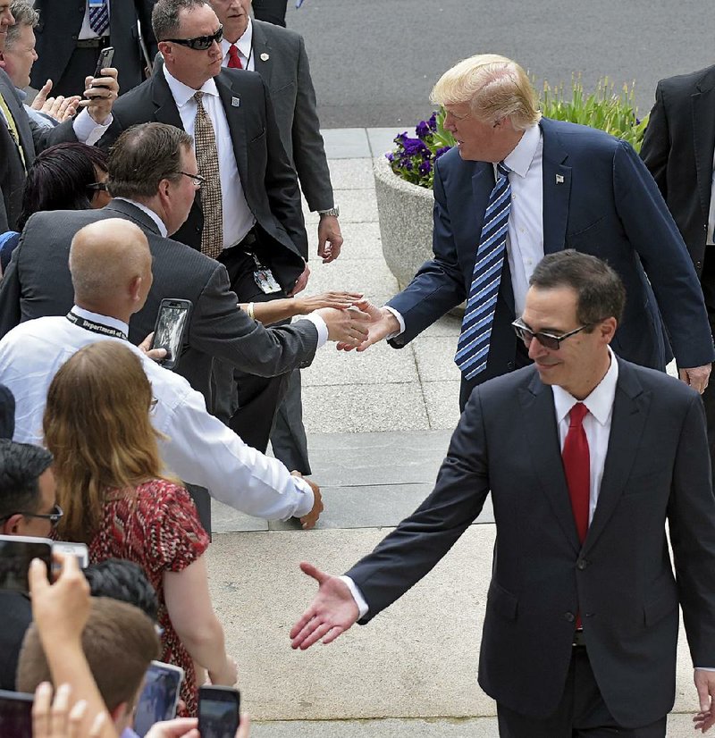 President Donald Trump and Treasury Secretary Steve Mnuchin greet people Friday as they arrive at the Treasury Department in Washington. Trump said the tax package he expects to unveil next week will hold cuts that will be “bigger, I believe, than any tax cut ever.”