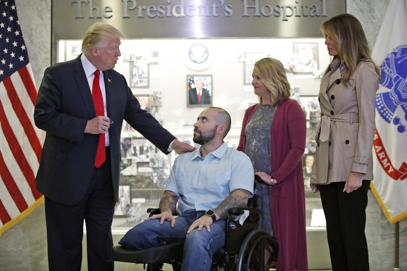President Donald Trump prepares to award a Purple Heart to U.S. Army Sgt. 1st Class Alvaro Barrientos, with first lady Melania Trump, right, and Tammy Barrientos, second from right, at Walter Reed National Military Medical Center, Saturday, April 22, 2017, in Bethesda, Md. 