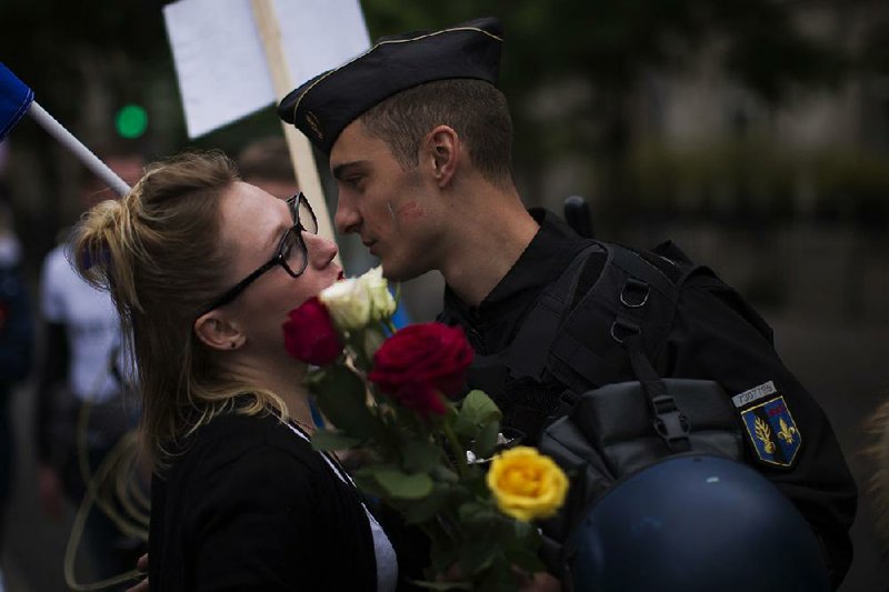 A woman kisses a French police officer after giving him flowers Saturday near the Eiffel Tower in Paris during a demonstration of support for French security forces on guard for the election.