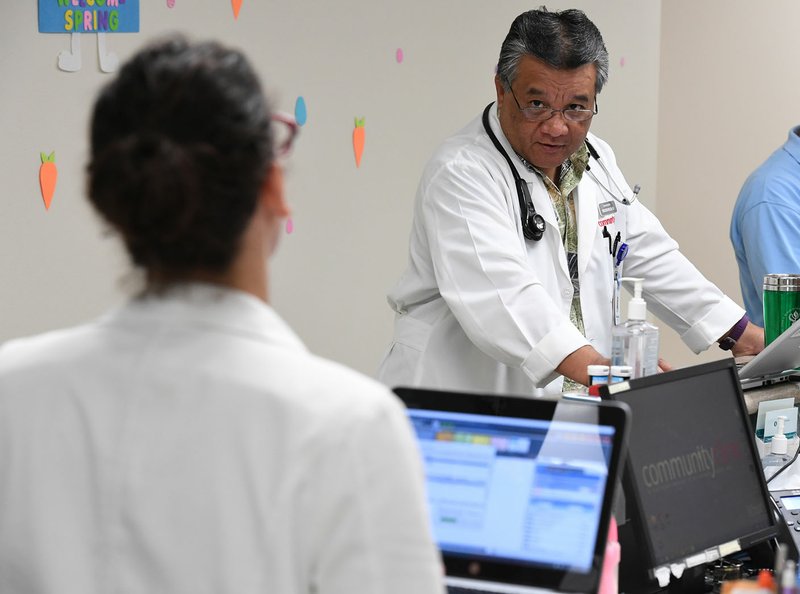 NWA Democrat-Gazette/J.T. WAMPLER Dr. Sheldon Riklon speaks Friday with colleague Dr. Claire Servy at the Community Clinic in Springdale. Riklon splits his time between being an associate professor at the University of Arkansas for Medical Sciences and seeing patients at the clinic.