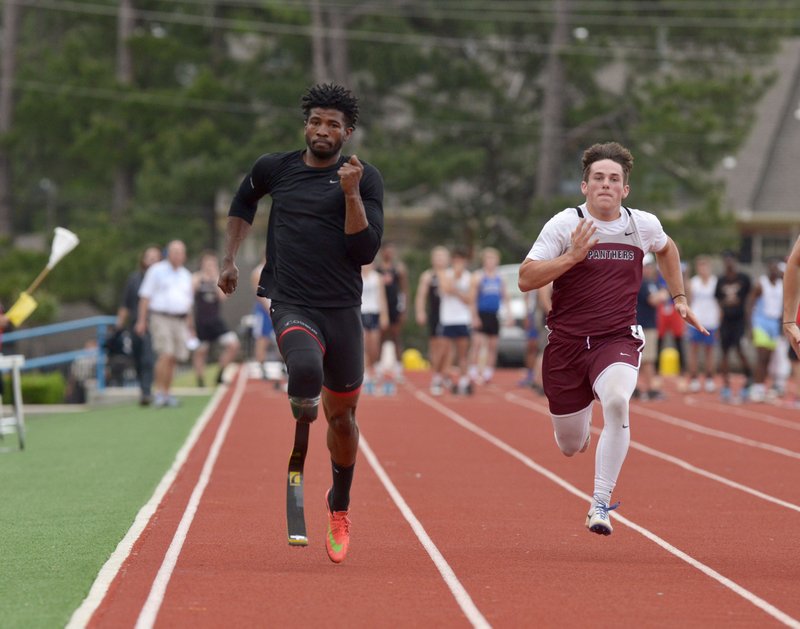 Richard Browne (left), a member of the 2012 U.S. Paralympic Team, from Jackson, Miss., runs alongside Kaiden Thrailkill of Siloam Springs on Thursday in the first heat of the 100-meter dash during the Never Say Never Foundation’s Battle of the Blades at the McDonald’s Relays at Fort Smith Southside.