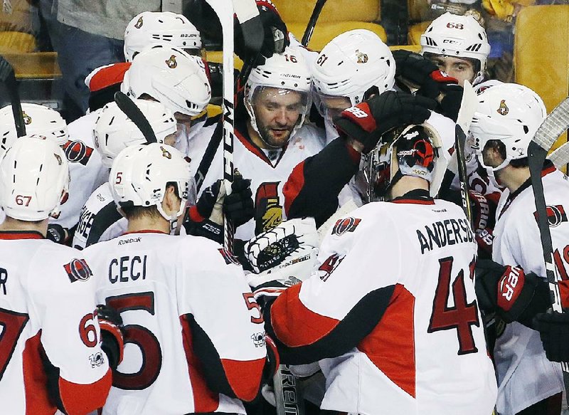Ottawa forward Clarke MacArthur (center) is surrounded by teammates after his overtime goal pushed the Senators past Boston 3-2 to win their NHL Eastern Conference playoff series Sunday.