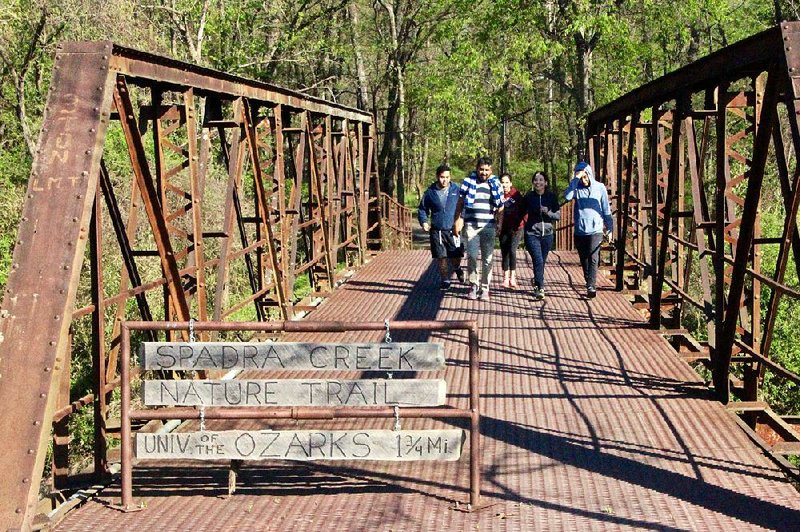 Walkers cross the old iron bridge at the southern trailhead of Clarksville’s Spadra Creek Nature Trail.
