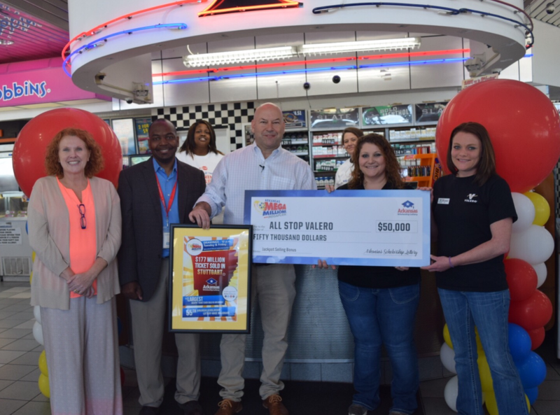 Lottery officials including director Bishop Woosley, center, present an oversized bonus check to workers at a Stuttgart gas station that sold a $177 million-winning Mega Millions ticket.