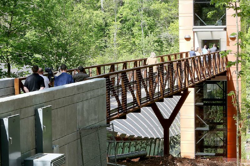 Visitors and staff members on Tuesday walk across the new 100-foot pedestrian bridge on the north side of Crystal Bridges Museum of American Art in Bentonville.