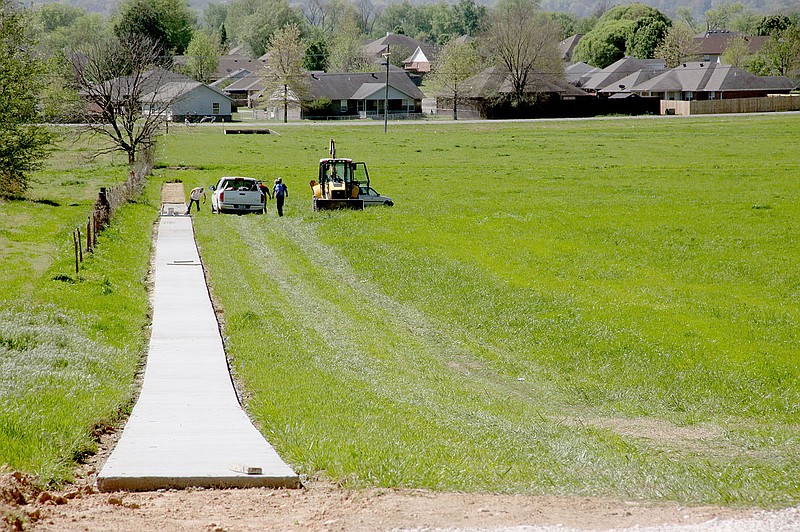 LYNN KUTTER ENTERPRISE-LEADER Prairie Grove public works employees are installing .42 mile of sidewalk in this field from Bush Street in front of Prairie Grove High School to U.S. 62 B. The sidewalk will connect subdivisions and residential areas on the south side of the highway to school campuses.