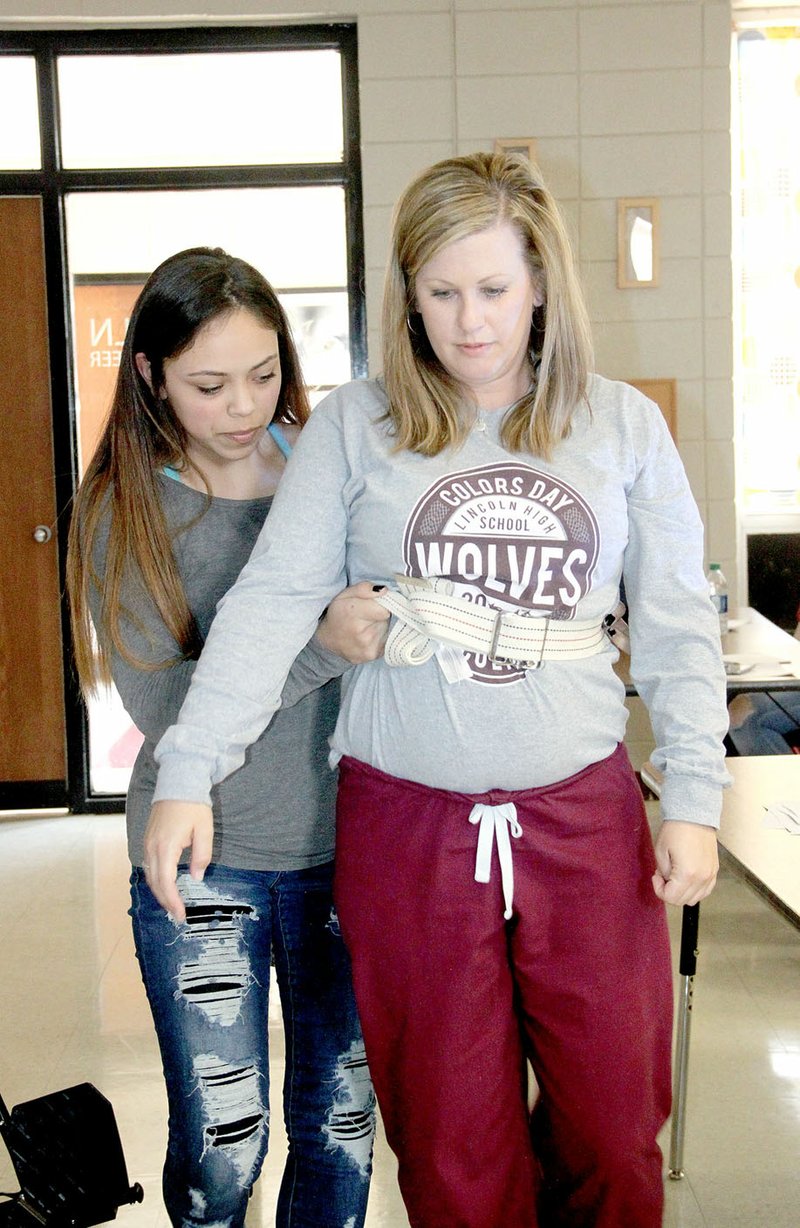 LYNN KUTTER ENTERPRISE-LEADER Jazmin Correa shows the proper way to use a gait belt with Emily Stephens, instructor in Lincoln High School&#8217;s Health Career Training Academy. Twenty-four students have gone through the program this semester to be certified as a personal care assistant.