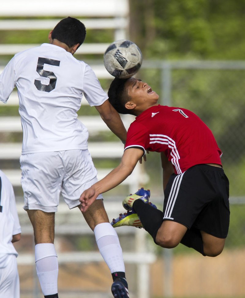 NWA Democrat-Gazette/JASON IVESTER Springdale sophomore Jose Vega (right) and Bentonville senior Mauricio Osorio vie for a header Tuesday, April 25, 2017, at the Tiger Athletic Complex in Bentonville.