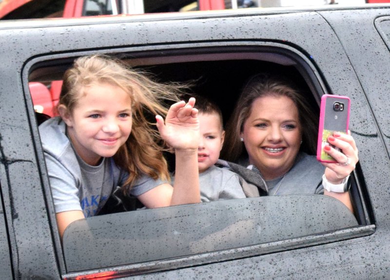 From the rear window of their limousine, Remington Anderson (center) and one of his sisters wave to the many fire fighters lining Main Street in Decatur April 20 as their mother Tina takes a video of the event.