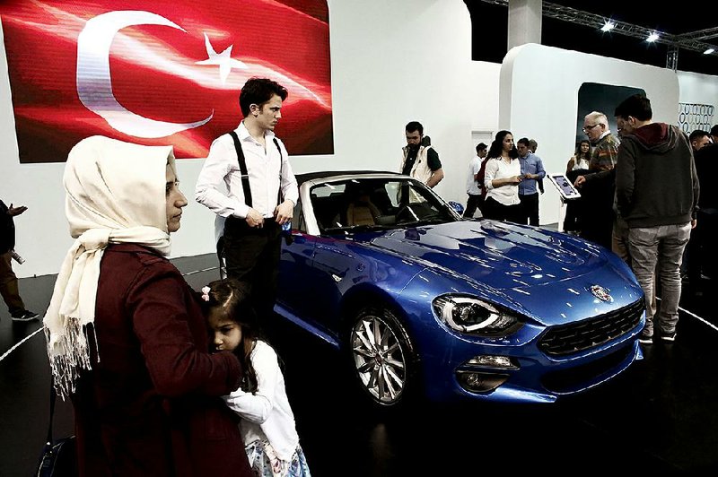 Visitors look at a Fiat 124 Spider sports car, manufactured in Turkey by Fiat Chrysler Automobiles NV, at the Istanbul Autoshow in Buyukcekmece, Turkey, on Sunday. 