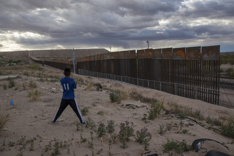 In this March 29, 2017 file photo, a youth looks at a new, taller fence being built along U.S.-Mexico border, replacing the shorter, gray metal fence in front of it, in the Anapra neighborhood of Ciudad Juarez, Mexico, across the border from Sunland Park, New Mexico. 