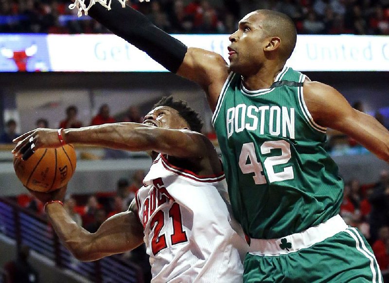 Al Horford (right) of the Boston Celtics defends a shot by Jimmy Butler of the Chicago Bulls during Friday night’s game. The Celtics won 105-83 to clinch the fi rst-round NBA playoff series.