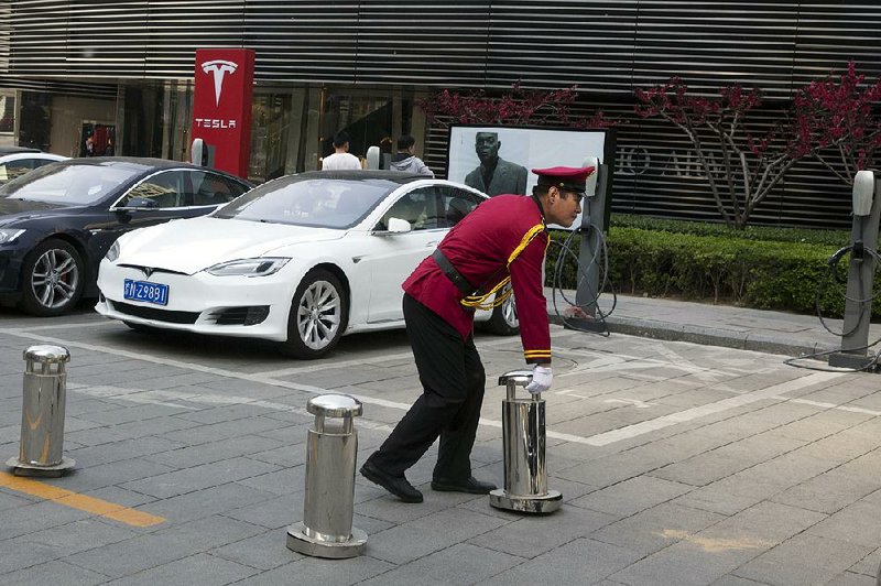 A security guard removes a barricade near a Tesla charging station earlier this month in Beijing. Tesla’s stock continues to rise as short sellers acquire shares, betting that the company will fail to meet its electric-car goals.