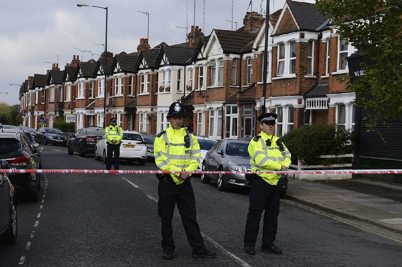 Police officers guard a cordoned-off area in London on Friday, a day after a counterterrorism raid that left a woman wounded.