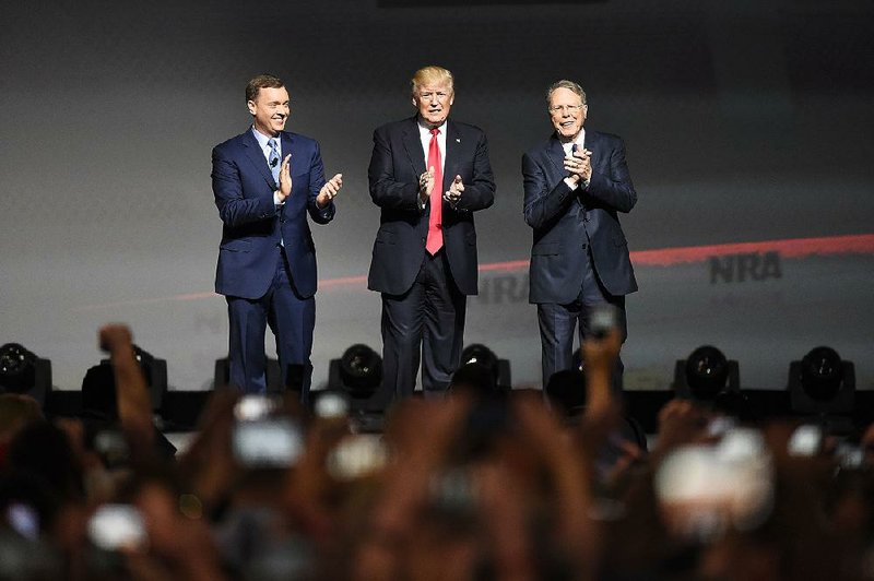 President Donald Trump stands with National Ri•e Association Executive Vice President Wayne LaPierre (right) and Chris Cox, an NRA executive, as he arrives at the NRA convention Friday in Atlanta.