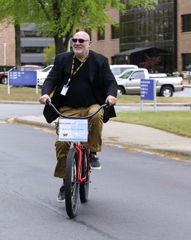 Acxiom CEO and President Scott Howe rides a bicycle between buildings earlier this month at the company’s corporate headquarters in Conway. Howe said that Acxiom today reminds him of Amazon when it first began expanding its business beyond books. 