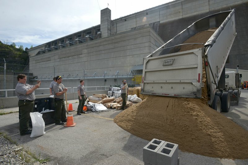 A truck dumps a load of sand as Beaver Lake park rangers fill sandbags Thursday at the Beaver Dam power plant near Eureka Springs. With heavy rain in the forecast for the weekend, Army Corps of Engineers staff are building barriers to protect the power plant and adjacent switching yard from flooding if they need to release a large amount of water from the dam’s floodgates.