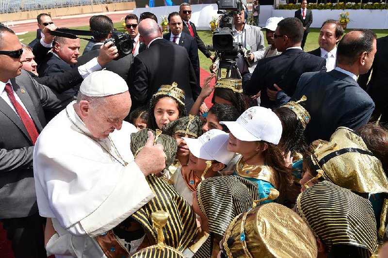 Surrounded by guards Saturday in Cairo, Pope Francis greets children — some of whom are dressed in ancient Egyptian costumes — before celebrating Mass.