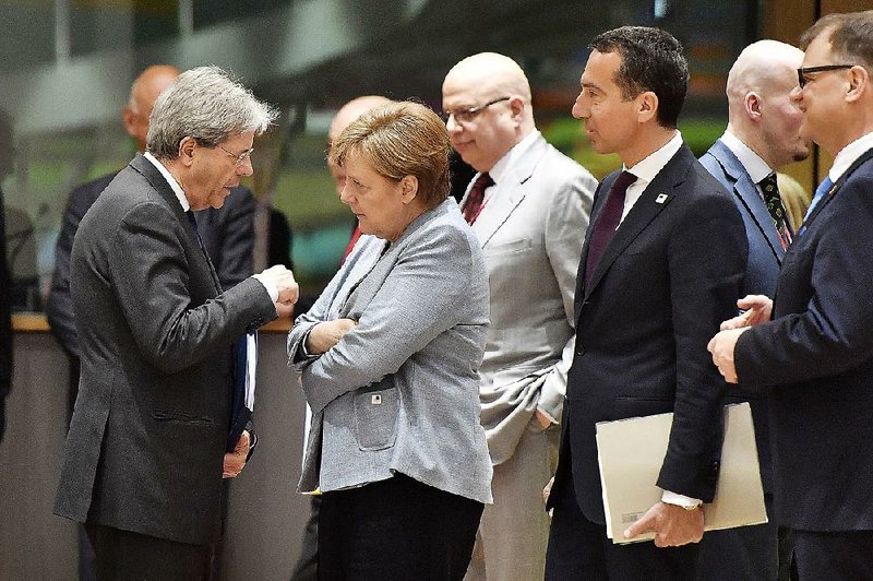 Italian Prime Minister Paolo Gentiloni talks Saturday with German Chancellor Angela Merkel as Austrian Chancellor Christian Kern looks on before a roundtable meeting at a European Union summit in Brussels.