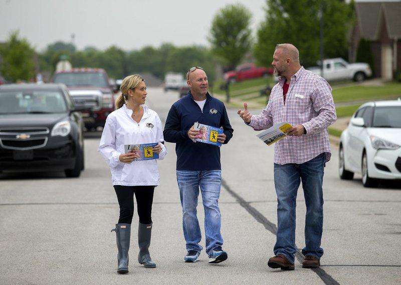 Ashlee Shumway (from left), Bryan Pratt and Eric White walk along Beasley Drive in Centerton passing out literature to residences Friday to promote a millage increase to voters.