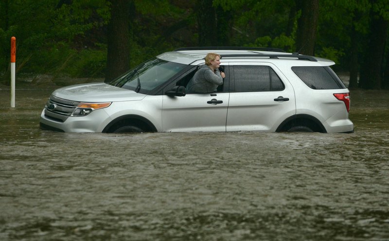 April Scott of Bella Vista waits for help Saturday after her Ford Explorer became stuck in high water on South 52nd Street in Rogers. Scott was able to exit the vehicle unassisted while waiting for a tow truck.