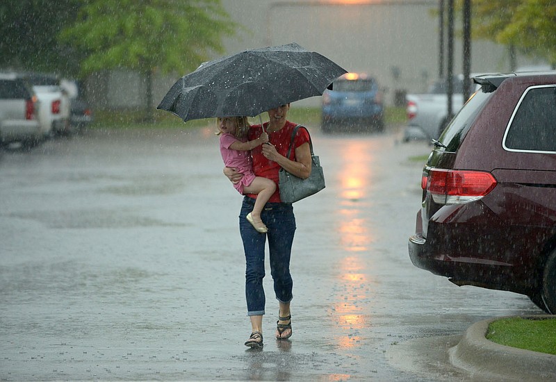 NWA Democrat-Gazette/BEN GOFF @NWABENGOFF Megan Hughey of Lowell carries her daughter Blythe Hughey, 3, through the rain Saturday, April 29, 2017, as they arrive at the Bentonville Public Library.