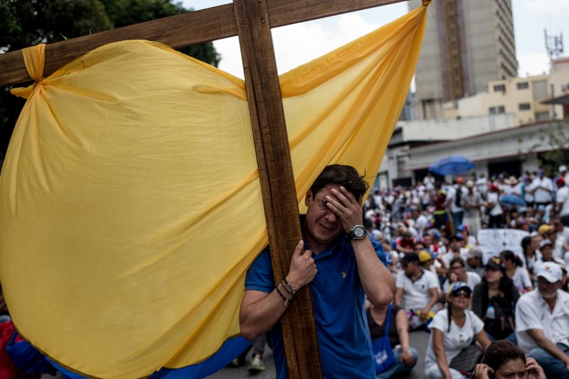 A man carries a cross as he leads a march to Venezuela's Episcopate. 