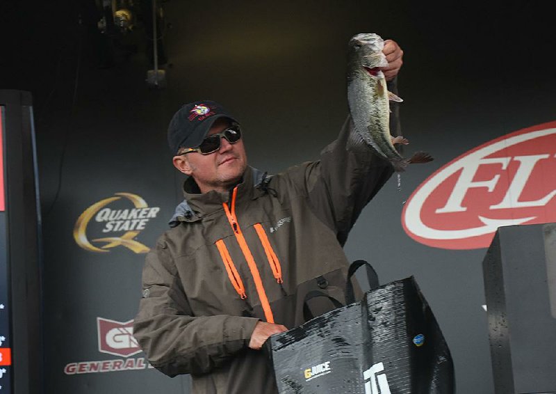 Johnny McCombs of Morris, Ala., shows one of the two largemouth bass he caught Sunday to win the FLW Tour bass tournament at Beaver Lake. McCombs fi nished the four-day event with a total weight of 47 pounds, 1 ounce.