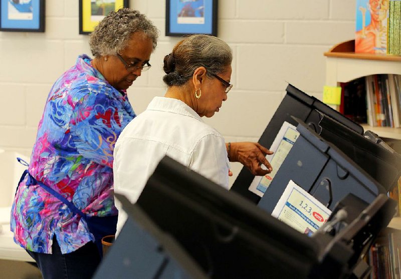 Election official Barbara Stewart (left) assists early voter Gloria M. White-Owens at an electronic voting machine Tuesday in the Southwest Community Center on Baseline Road in Little Rock.