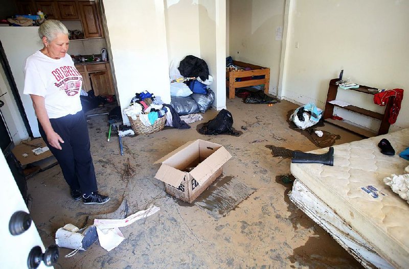 Tammy Linder looks at the damage and debris Tuesday in her home at the West End Apartments in Fayetteville. Rain and a swollen creek flooded the complex, causing extensive water damage in the apartments.