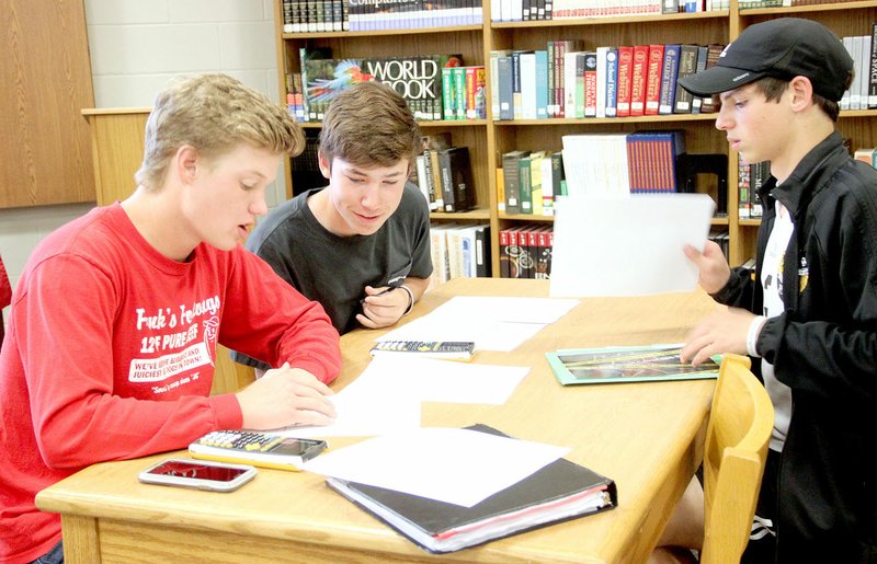 LYNN KUTTER ENTERPRISE-LEADER Ethan Scates, left, Drew Cates and Noah Akey try to figure out who murdered Al Gebra during their Algebra 2 class at Prairie Grove High School. Looking at evidence from the crime scene, Donna Mitchell&#8217;s students used math to try to solve the mystery. Prairie Grove was named the seventh best high school in the state by U.S. World &amp; News Report.