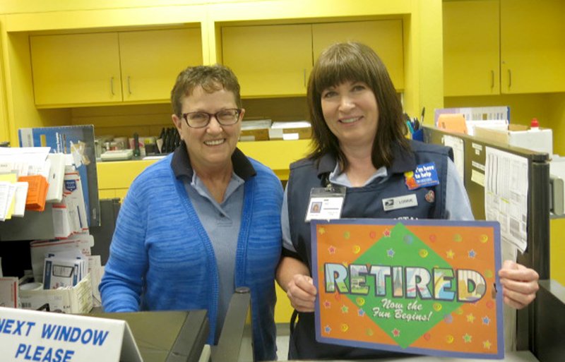 Photo by Susan Holland Lorrie Amos (right), on her last day of work at the Gravette Post Office, displayed the sign her coworkers gave her, reading &#8220;Retired, Now the Fun Begins!&#8221; Amos, retiring after more than 20 years at the Gravette office, posed with Karen Wilkins, a fellow mail clerk who will be moving up to fill her position.