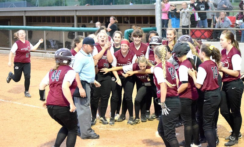 Photo by Mike Eckels Gentry players gather at home plate after Alyssa Kelton (44) hit a home run over the left outfield wall during the 4A district tournament softball game between Gentry-Lincoln April 27 in Gravette.