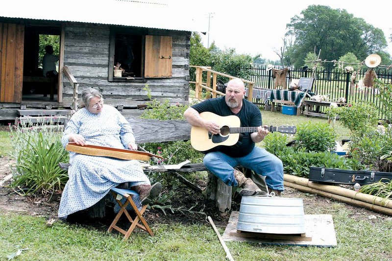 Melinda LaFevers of Searcy with the Friends of Pioneer Village dresses in period garb and plays her dulcimer for an impromptu concert with fellow musician Philip Baker of Searcy, whom she had just met at Spring Fest last year.