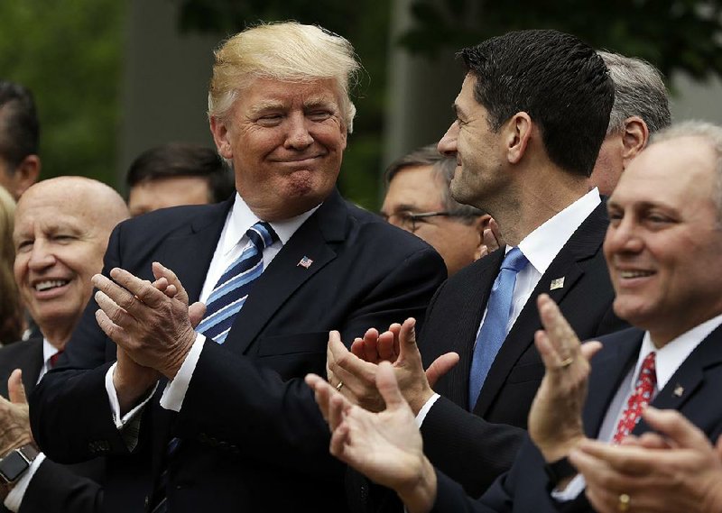 President Donald Trump celebrates with House Speaker Paul Ryan in the White House Rose Garden after the House passed the health care bill Thursday.