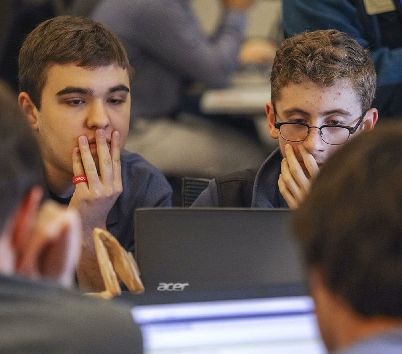 Noah Wehn (left) and Gregory Maddra, seniors at Har-Ber High School in Springdale, study their computer screen Thursday during the state’s first All-State Coding Competition.