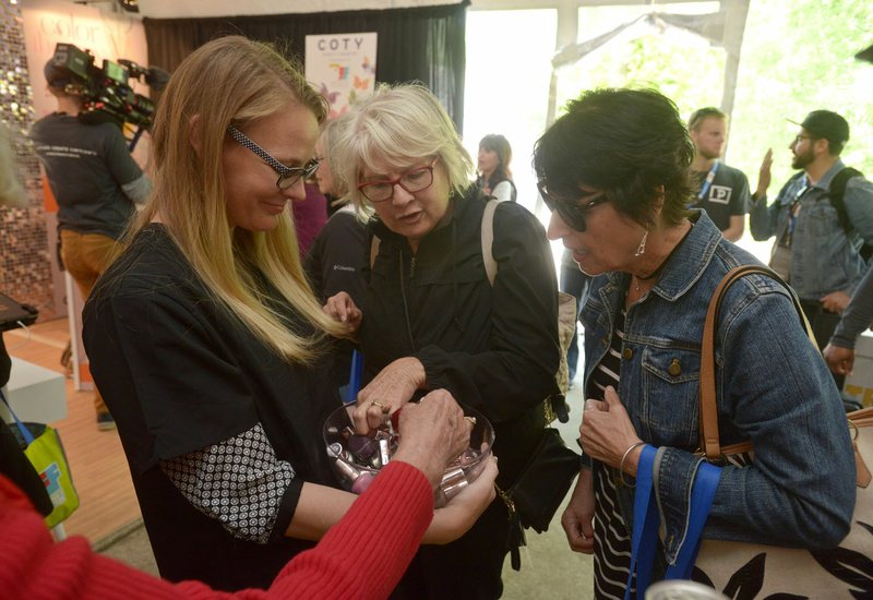 Ruthie McRae (from right) of Fort Smith and JoAnne Mills of Little Rock take samples of nail polish Thursday from Lauren Sullivan of Bentonville with Coty while walking through the Sponsor Village at Compton Gardens during the Bentonville Film Festival.
