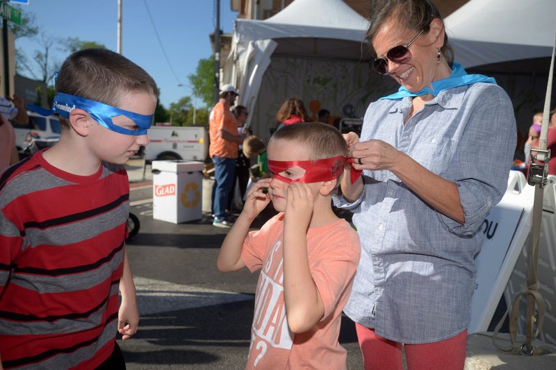 Tisha Brown of Centerton helps her sons Eli Brown (left), 10, and Jude Brown, 7, put on Teenage Mutant Ninja Turtles masks they picked up Friday while visiting booths in the Studio Lounge at the Bentonville Film Festival.