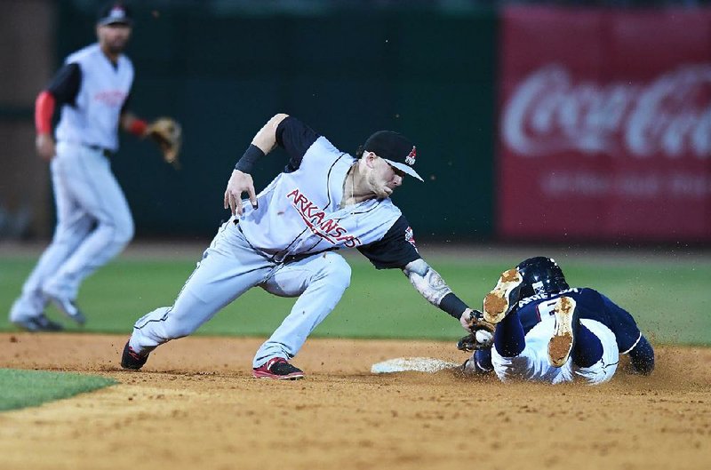 Arkansas second baseman Brock Hebert (left) applies a tag to Northwest Arkansas shortstop Humberto Arteaga as he tries to steal second base during the Naturals’ 4-0 victory over the Travelers on Saturday at Arvest Ballpark in Springdale.