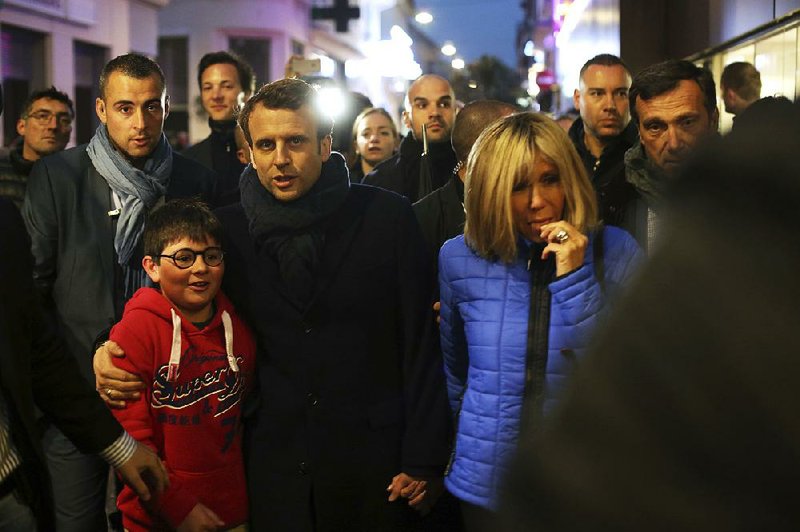 Emmanuel Macron and his wife, Brigitte, walk through a street Saturday near their home in Le Touquet in northern France. Macron, a centrist, faces far-right candidate Marine Le Pen in today’s presidential runoff election. 