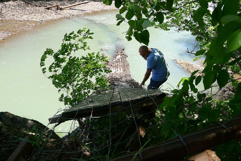Newell Holland of Clarksville looks at the ruins of a swinging bridge near Oark on Friday. The bridge was heavily damaged April 29 by floodwaters on the Mulberry River. Holland and other volunteers have worked to rebuild the bridge twice before. 