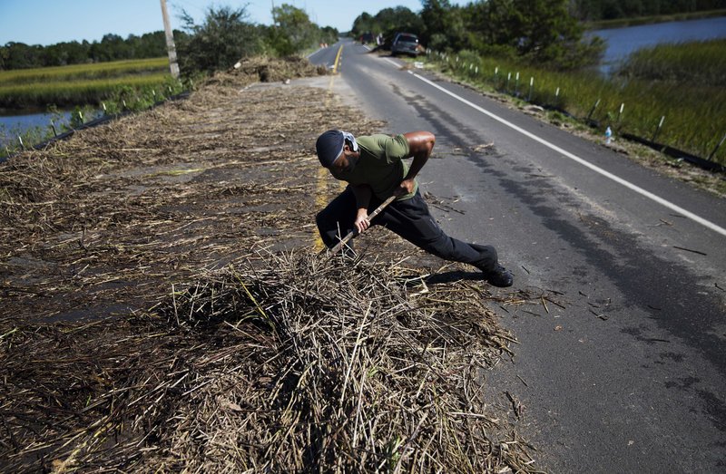 In this Oct. 9, 2016 file photo, Alex Bligen clears away debris from Hurricane Matthew that washed over the only road into Edisto Island, S.C. Republican-led South Carolina, which has long resisted tax increases, is among those seriously considering a gas tax hike in 2017 to pay for transportation improvements. 