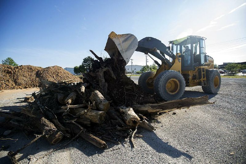 Dean Klingman, senior asset coordinator for the Benton County Road Department, adds to a pile of debris after recent storms Friday at the department.